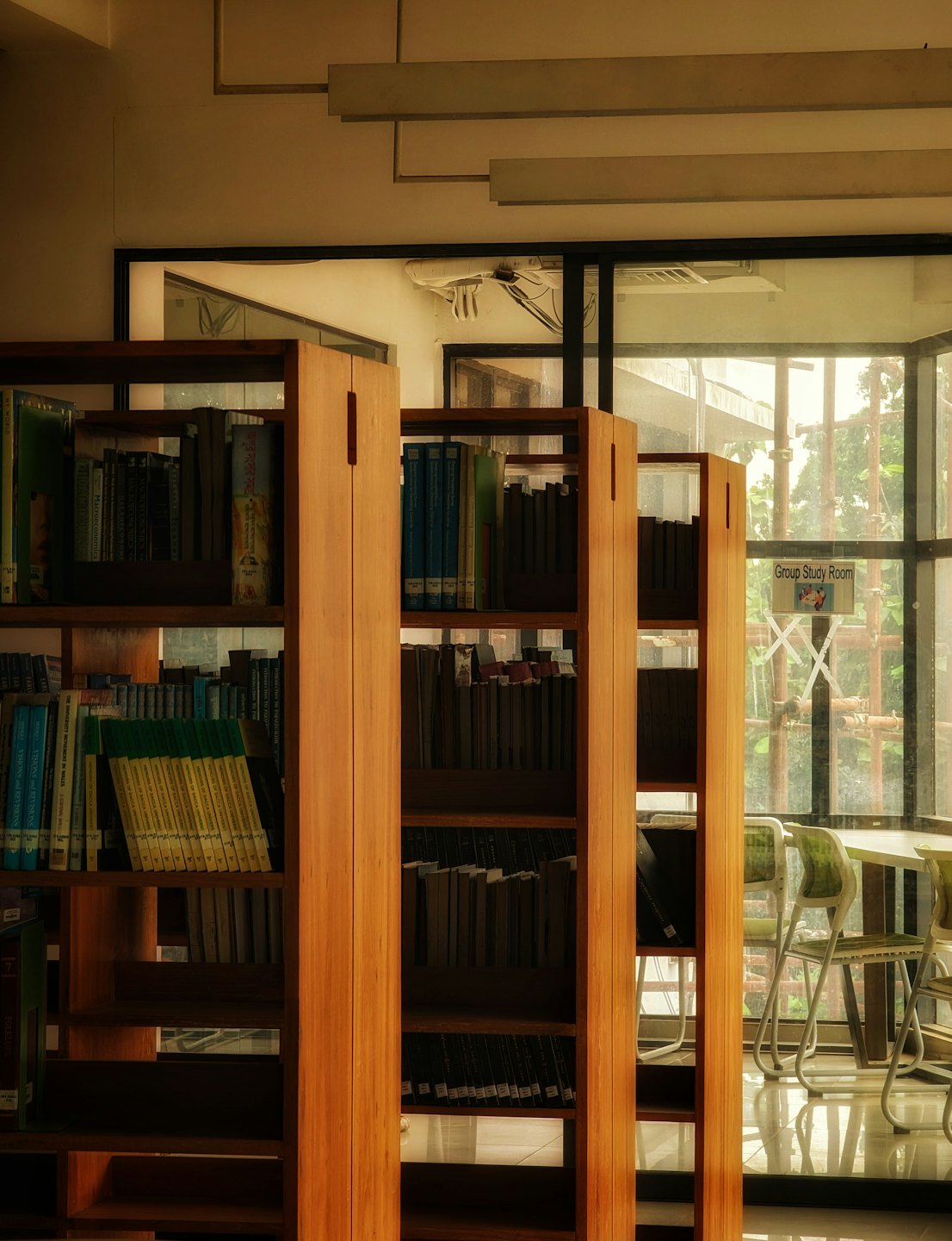 Drewniane regały w bibliotece z widocznym miejscem do siedzenia na zewnątrz.